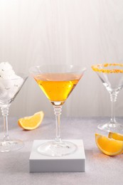 Tasty cocktails in glasses and orange slices on gray table