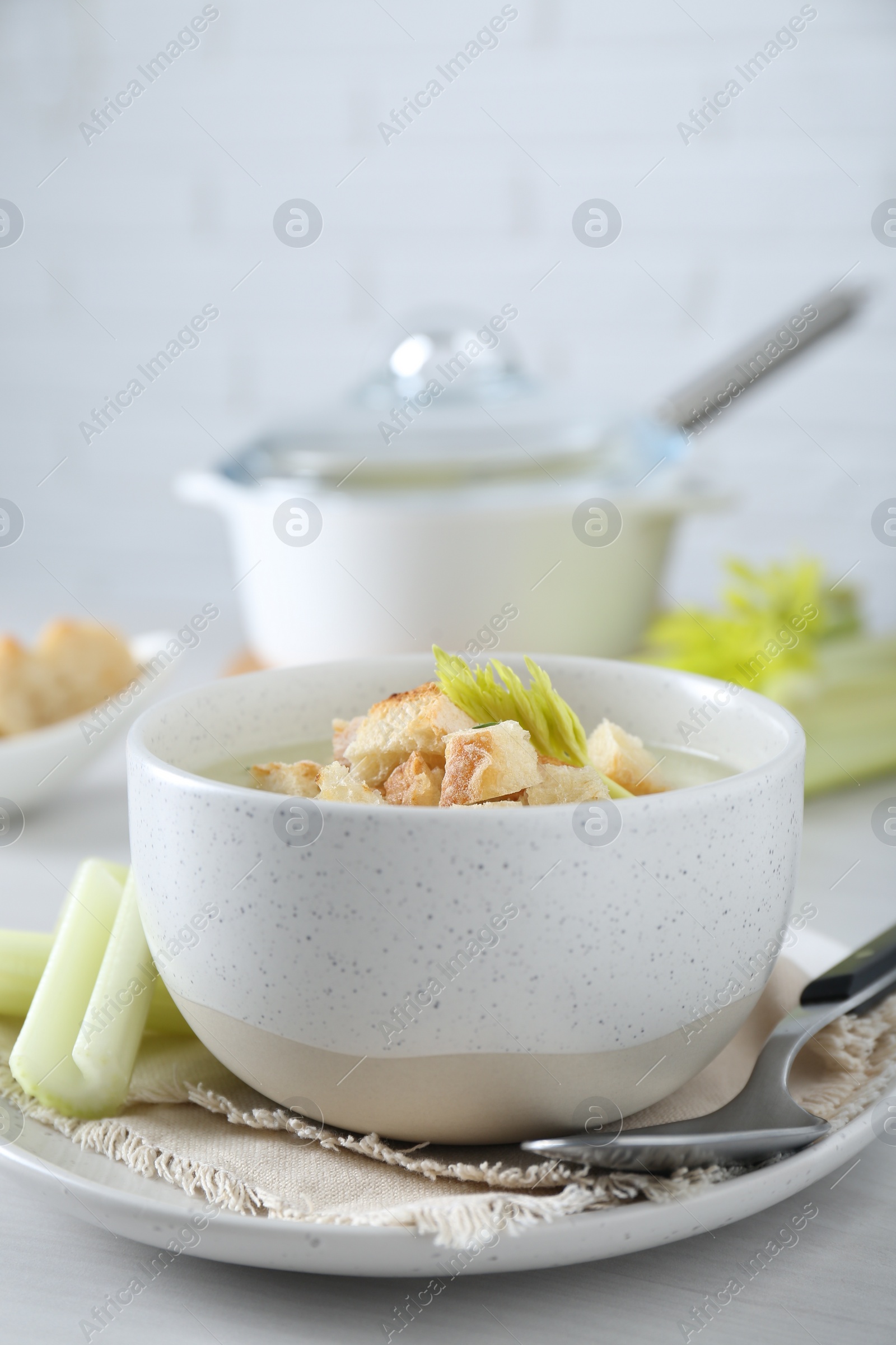 Photo of Bowl of delicious celery soup served on white table, closeup