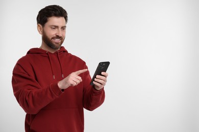 Photo of Happy man with smartphone on white background. Space for text