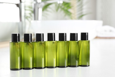 Mini bottles with cosmetic products on white table in bathroom