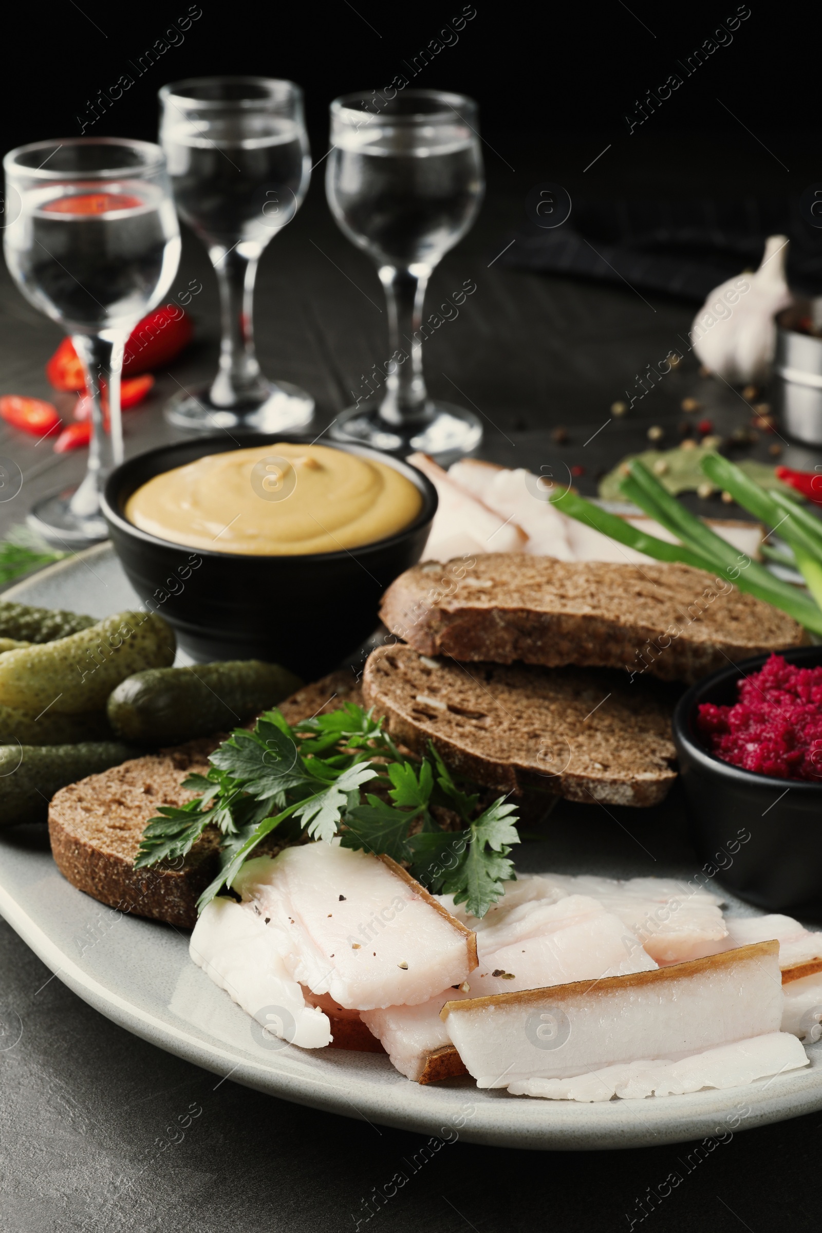 Photo of Tasty salt pork with rye bread served on grey table, closeup