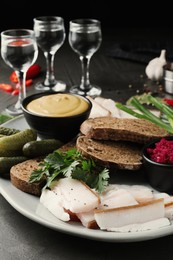 Photo of Tasty salt pork with rye bread served on grey table, closeup