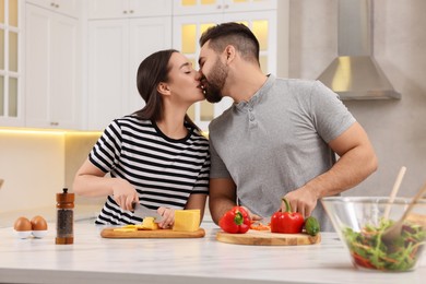 Photo of Lovely couple kissing while cooking in kitchen