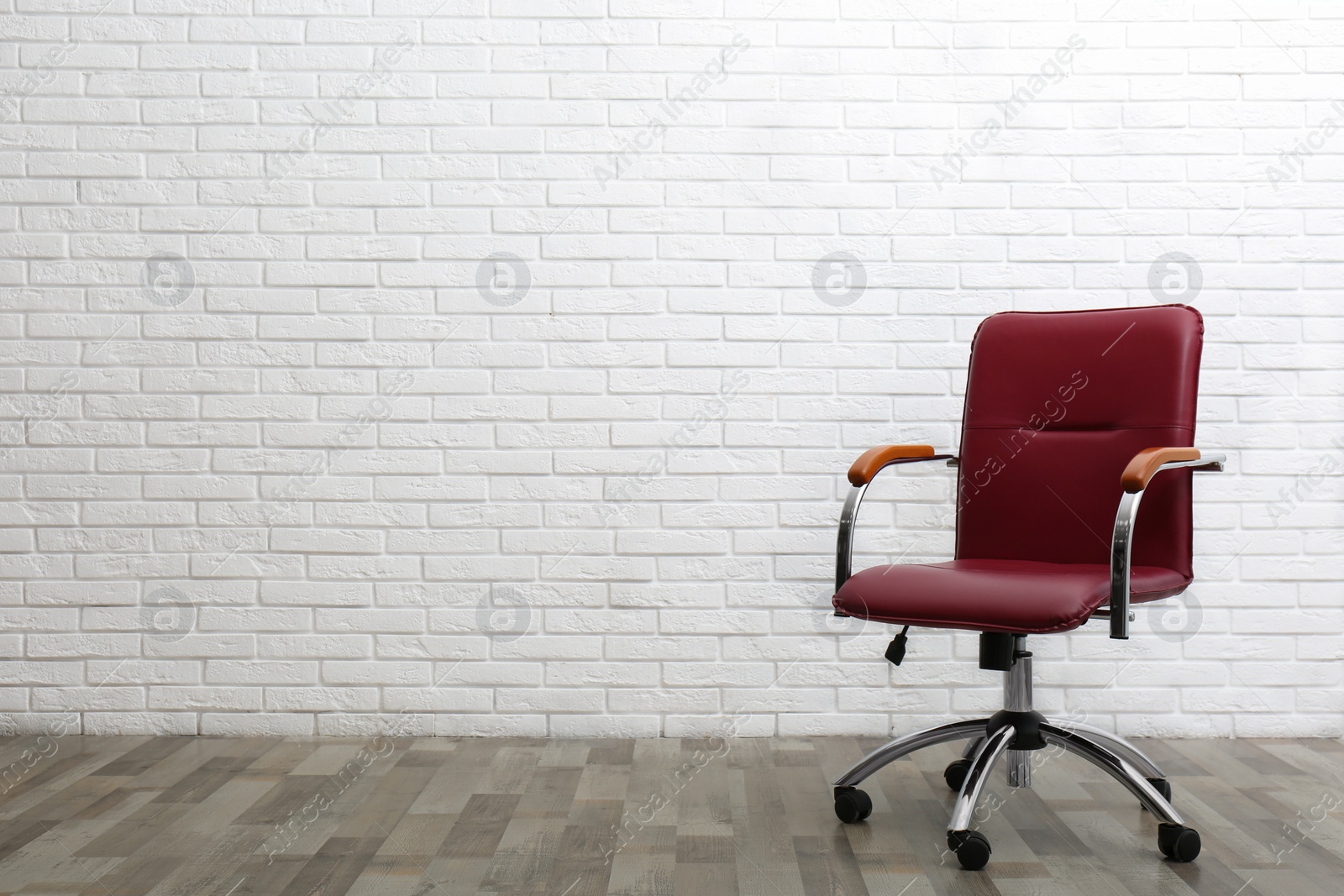 Photo of Comfortable office chair near white brick wall indoors. Space for text