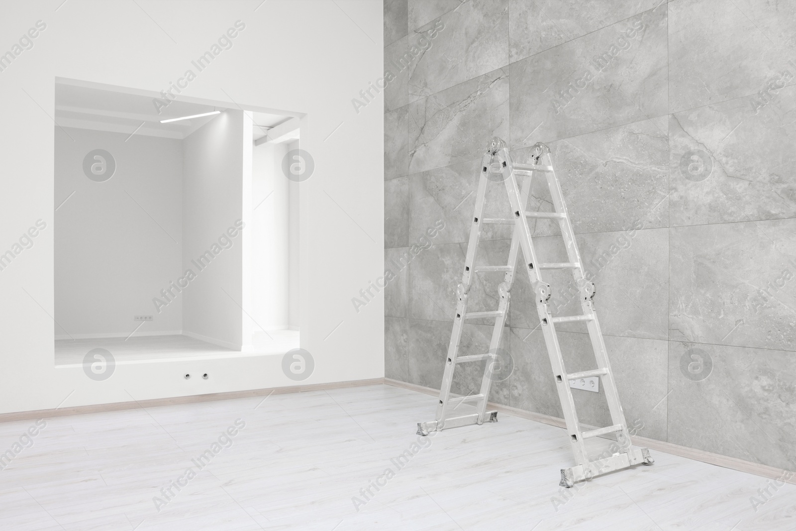 Photo of Empty room with tiled wall, ladder and opening for fake window during repair