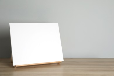 Photo of Wooden easel with blank canvas on table. Space for text