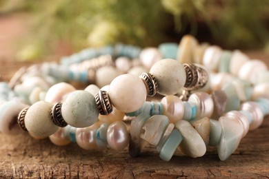 Beautiful bracelets with gemstones on wooden surface, closeup