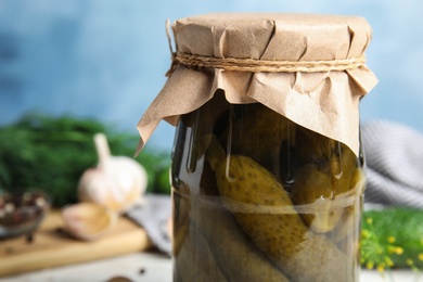 Photo of Jar with pickled cucumbers on white wooden table, closeup view