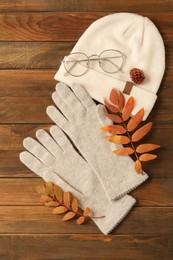 Flat lay composition with stylish woolen gloves and dry leaves on wooden table