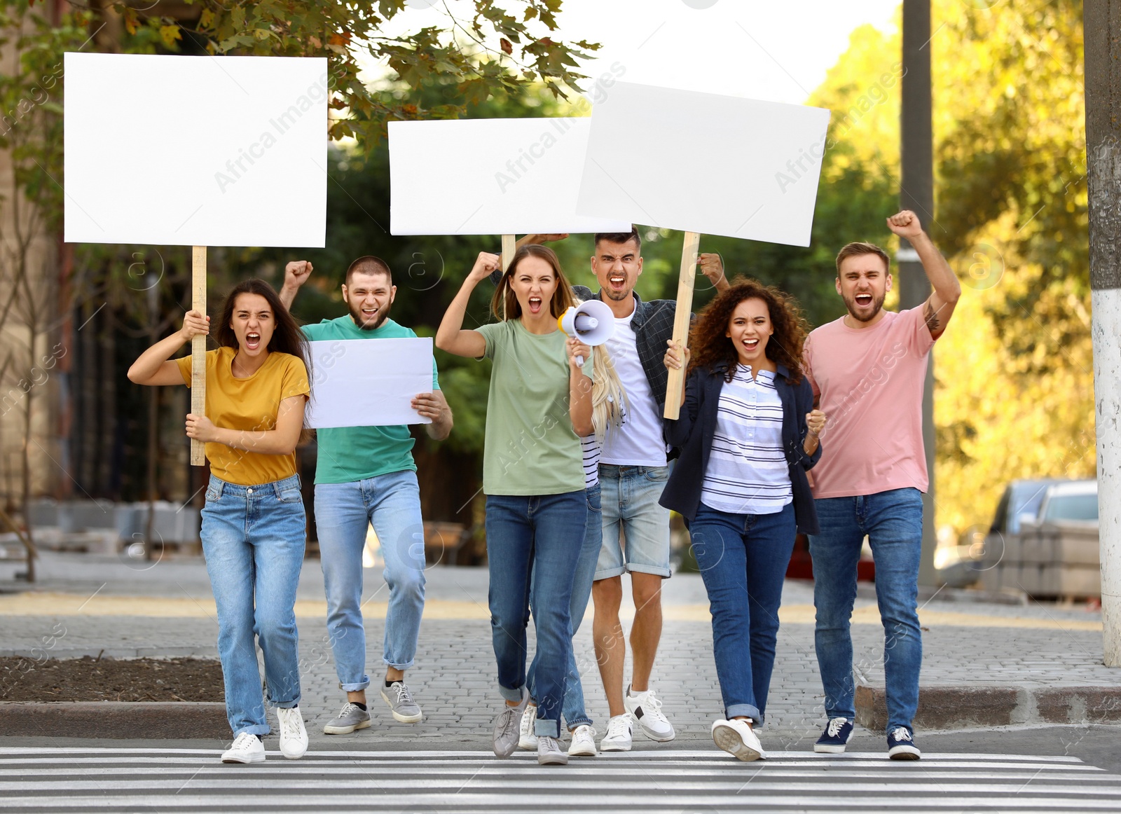 Photo of Emotional young woman with megaphone leading demonstration outdoors