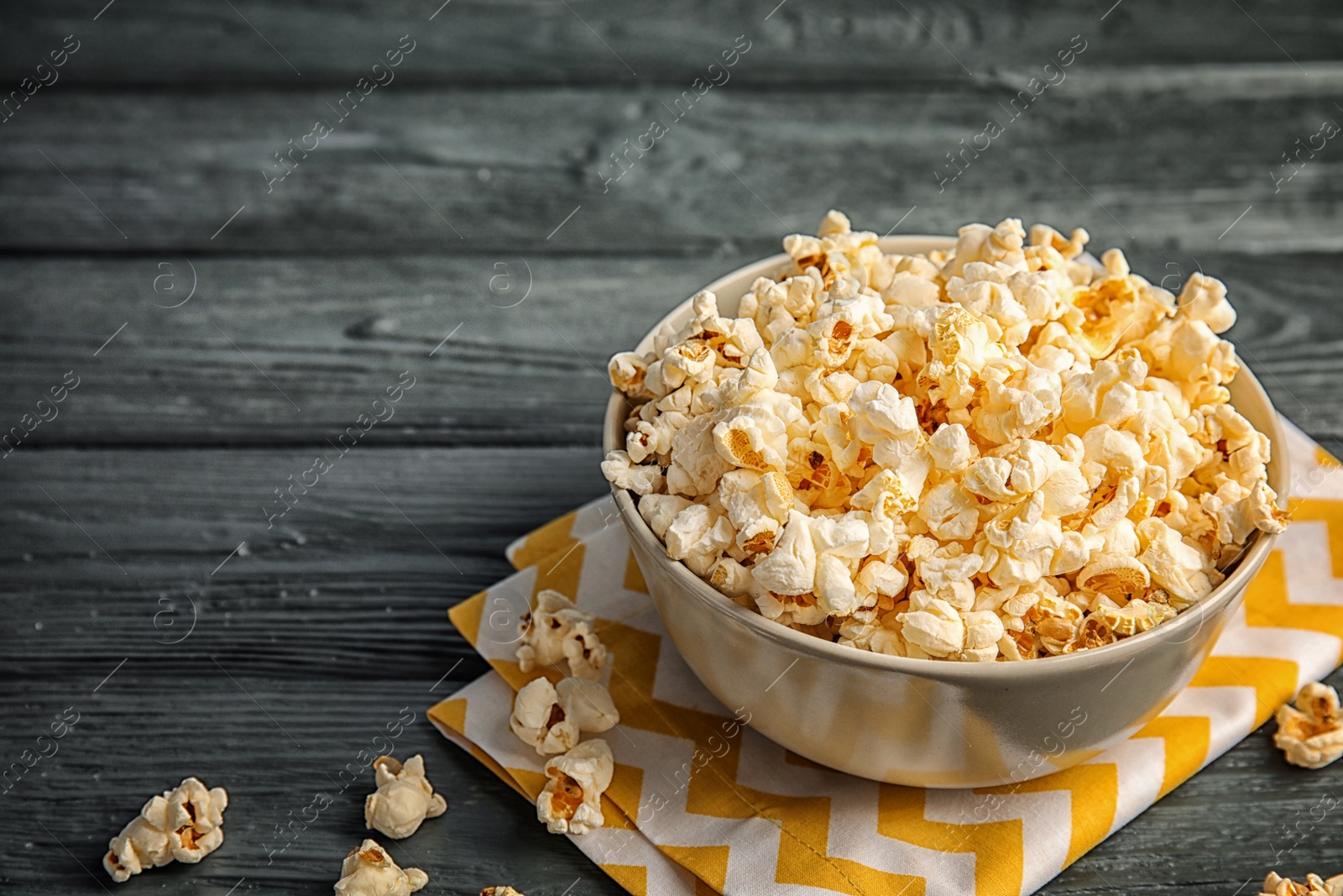 Photo of Bowl of tasty popcorn on wooden background