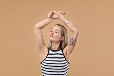 Portrait of beautiful tattooed woman on beige background