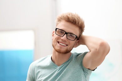 Portrait of handsome young man with glasses in room