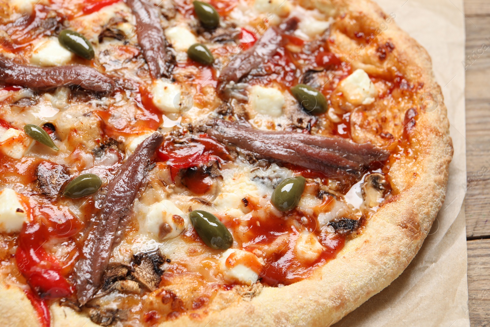 Photo of Tasty pizza with anchovies and olives on wooden table, closeup