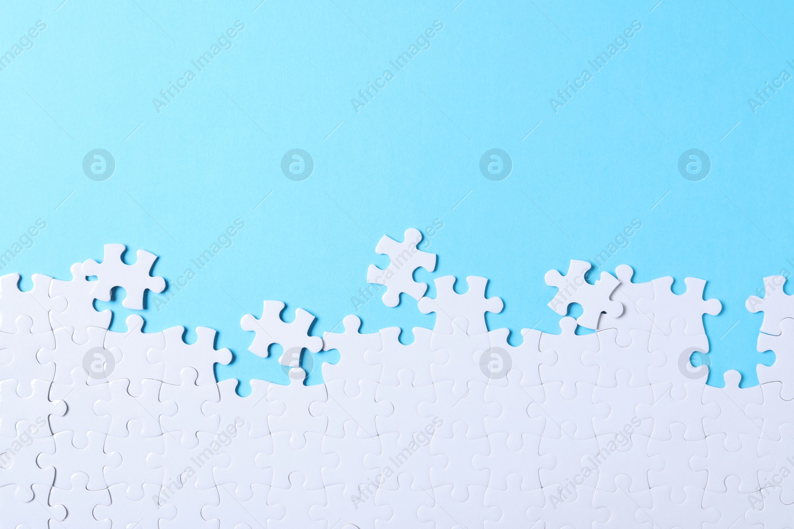 Photo of Blank white puzzle pieces on light blue background, flat lay. Space for text