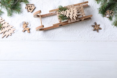 Photo of Flat lay composition with sleigh, fir tree branches and Christmas decorations on white wooden table. Space for text