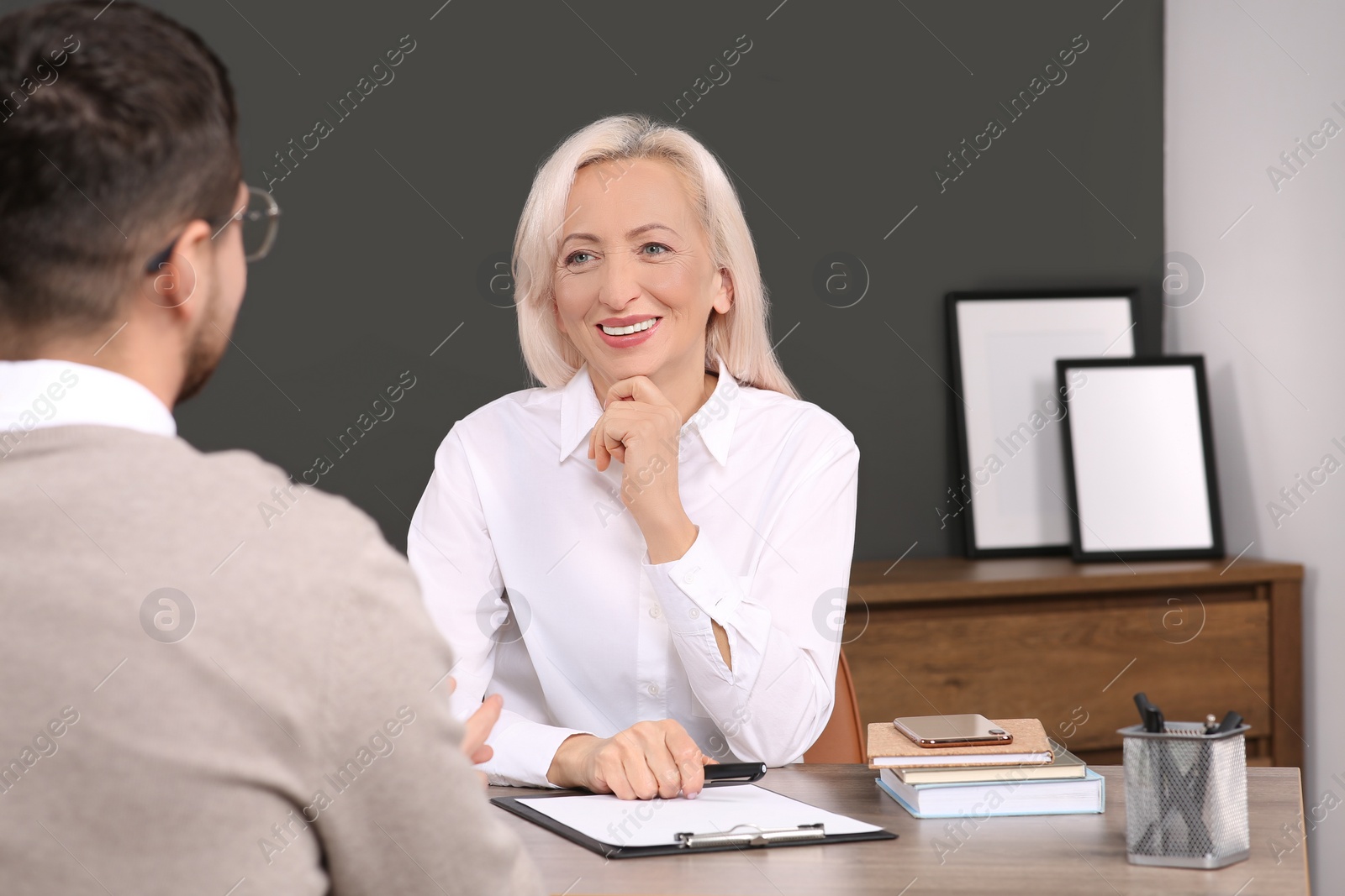 Photo of Happy woman having conversation with man at wooden table in office. Manager conducting job interview with applicant