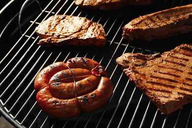 Photo of Fresh grilled tasty meat steaks and sausage on barbecue grate