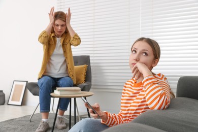 Teenage daughter with smartphone ignoring her mother at home