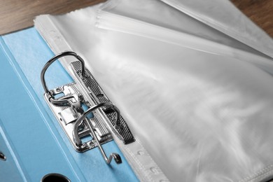 File folder with punched pockets on wooden table, closeup