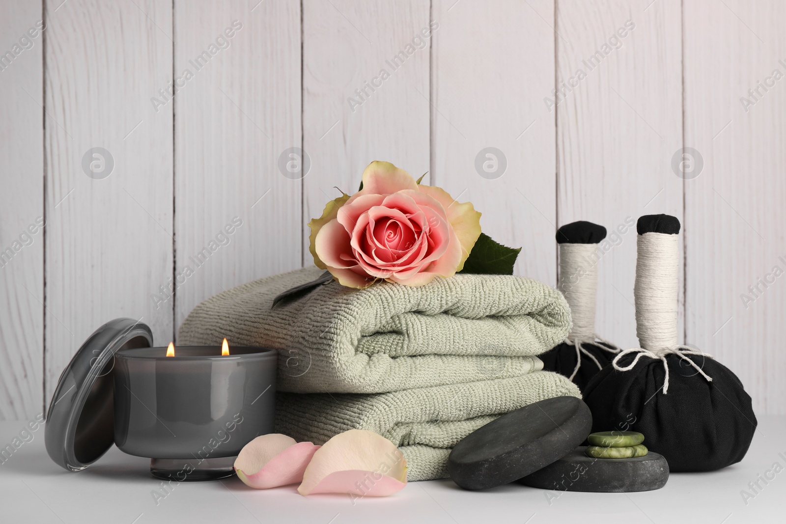 Photo of Composition with different spa products, rose and candle on white table against wooden background