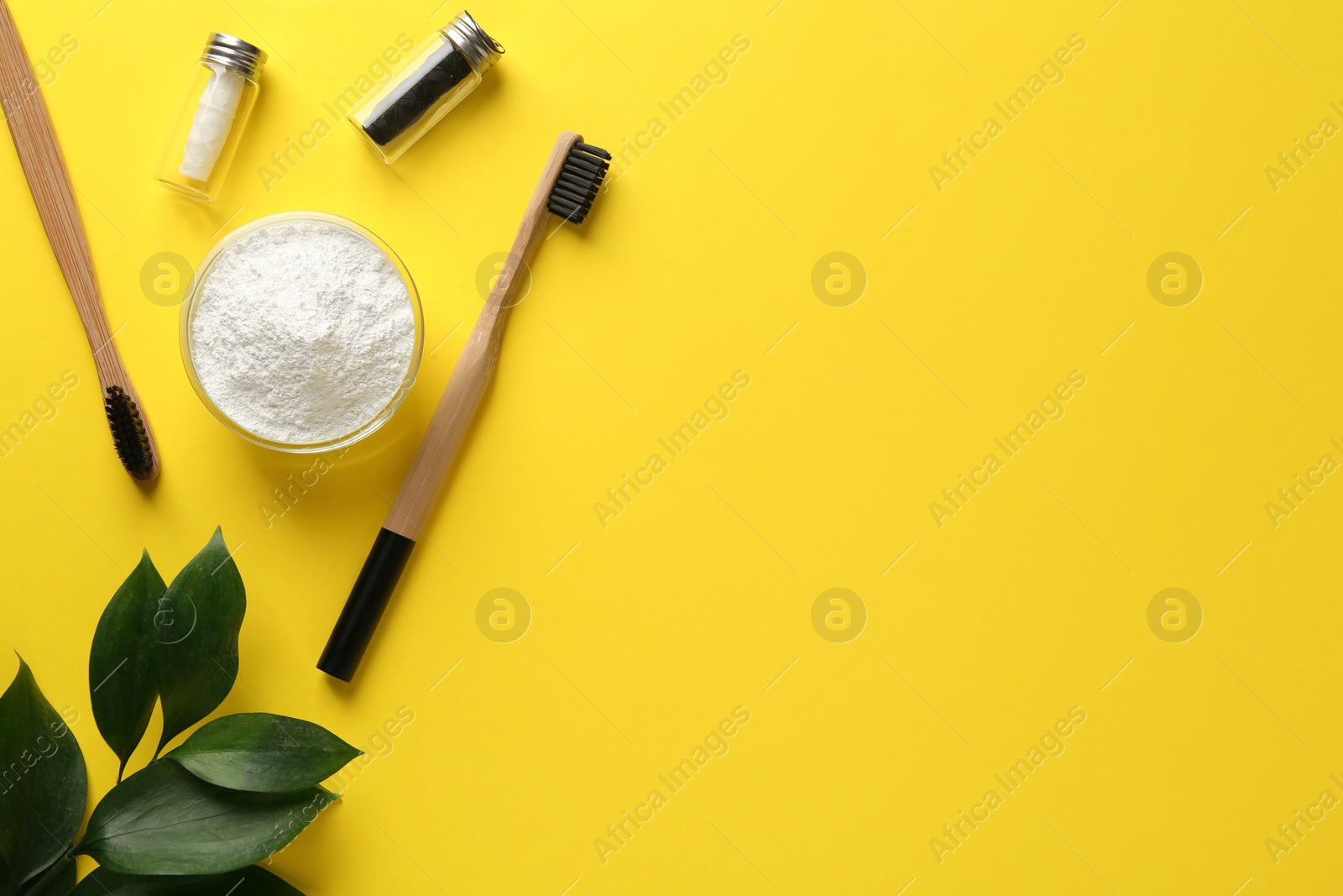 Photo of Bowl of tooth powder, brushes, dental flosses and plant on yellow background, flat lay. Space for text