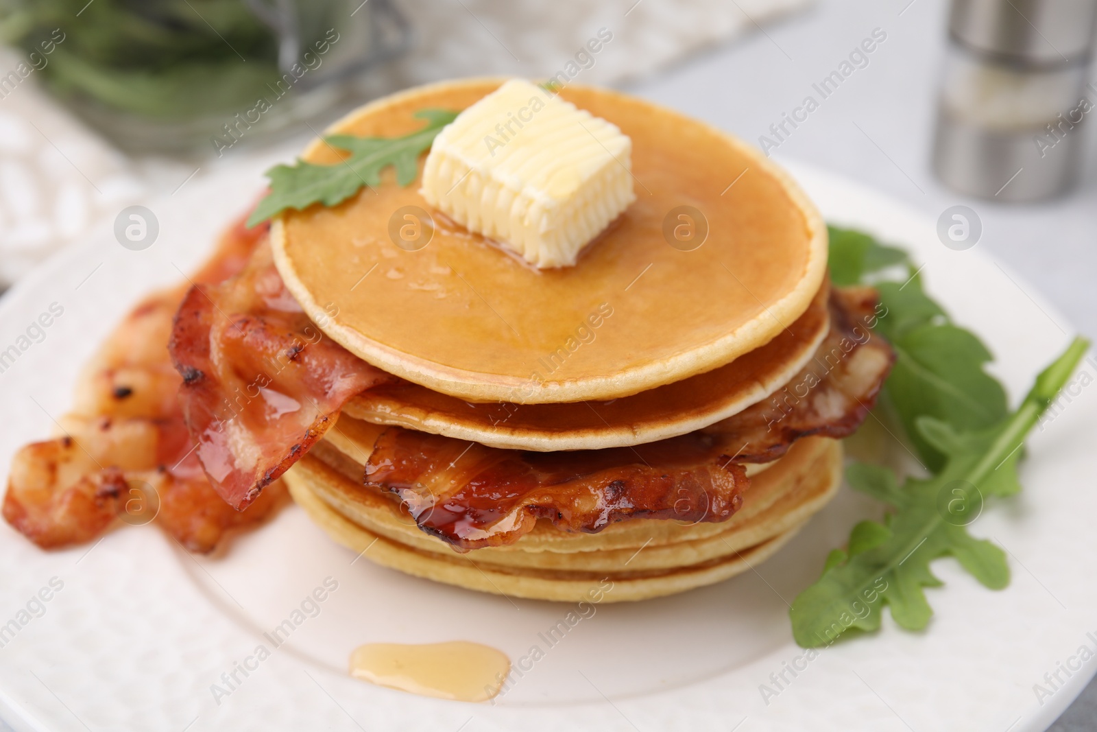 Photo of Delicious pancakes with bacon, butter and arugula on table, closeup