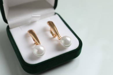 Elegant golden earrings in box on white table, closeup