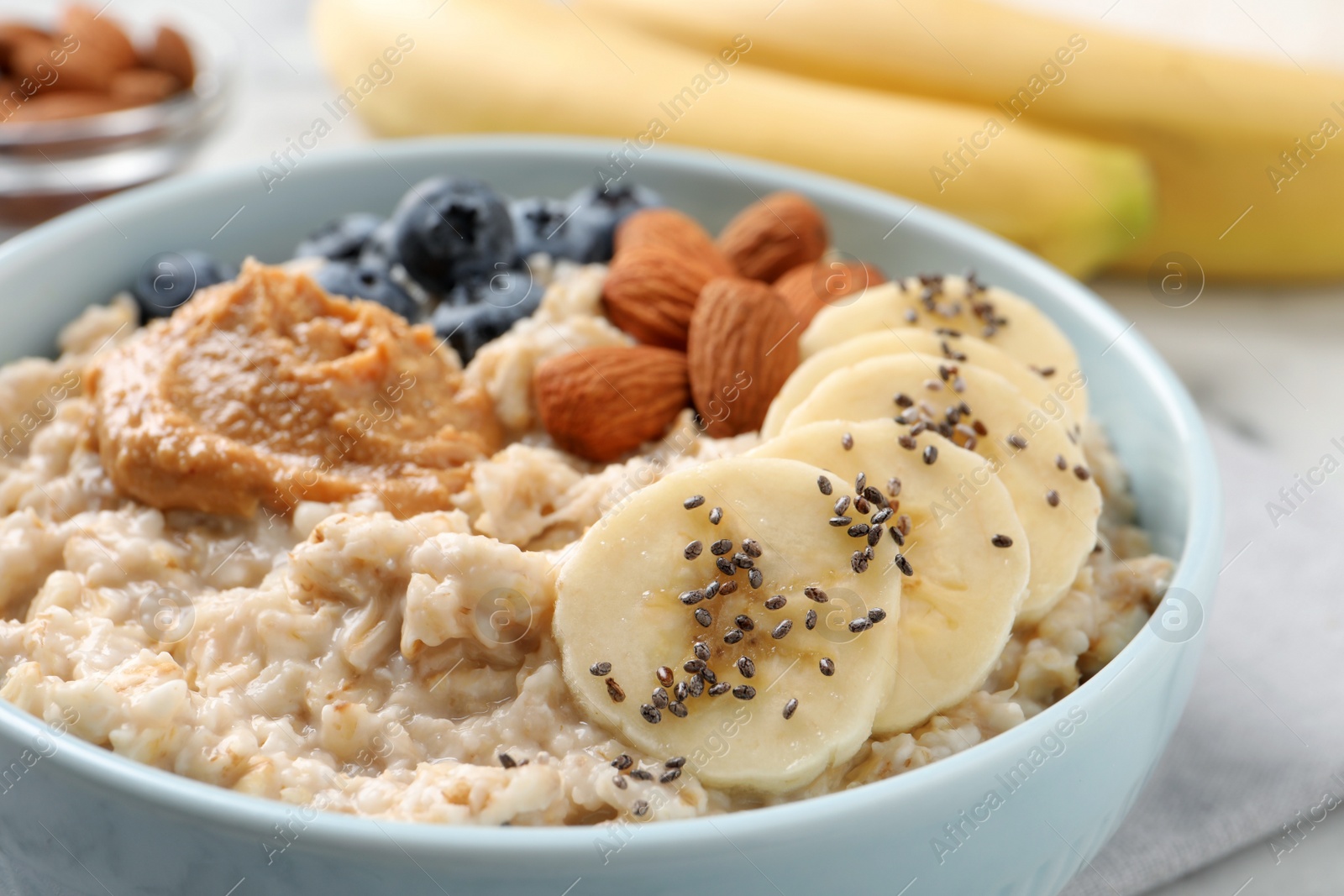 Photo of Tasty oatmeal porridge with toppings in bowl on table, closeup