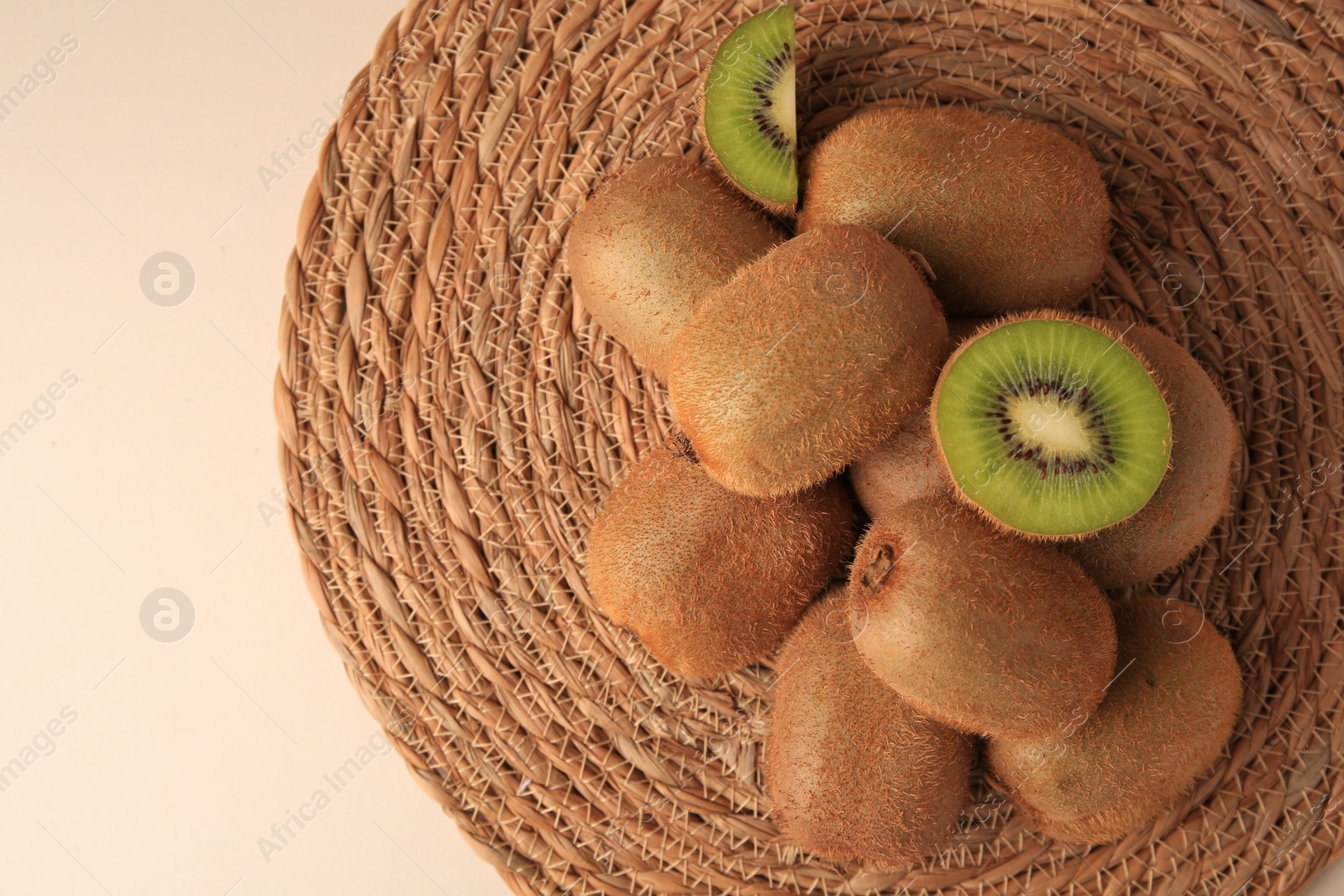 Photo of Heap of whole and cut fresh kiwis on white table, top view. Space for text