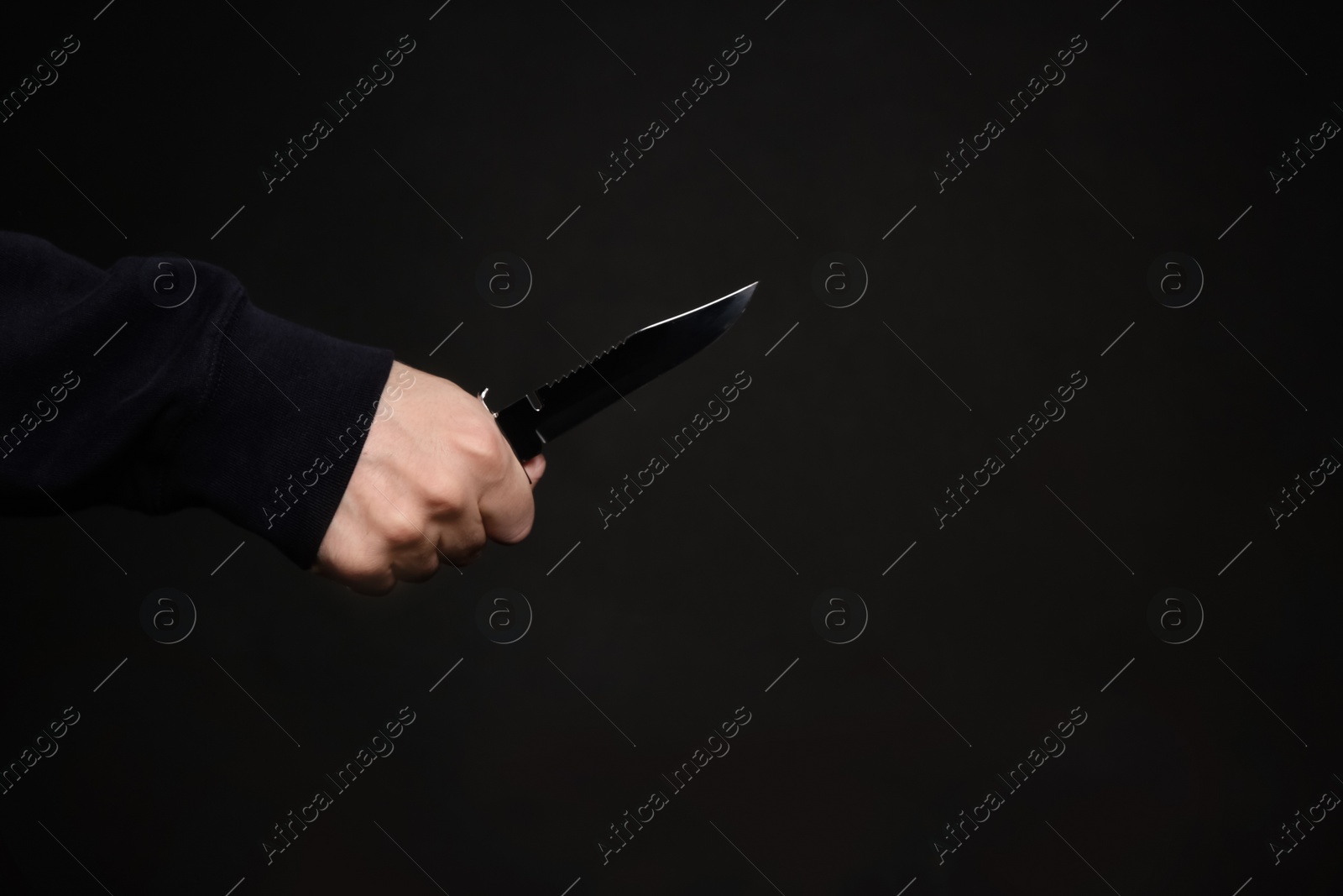 Photo of Man holding knife on black background, closeup with space for text. Dangerous criminal