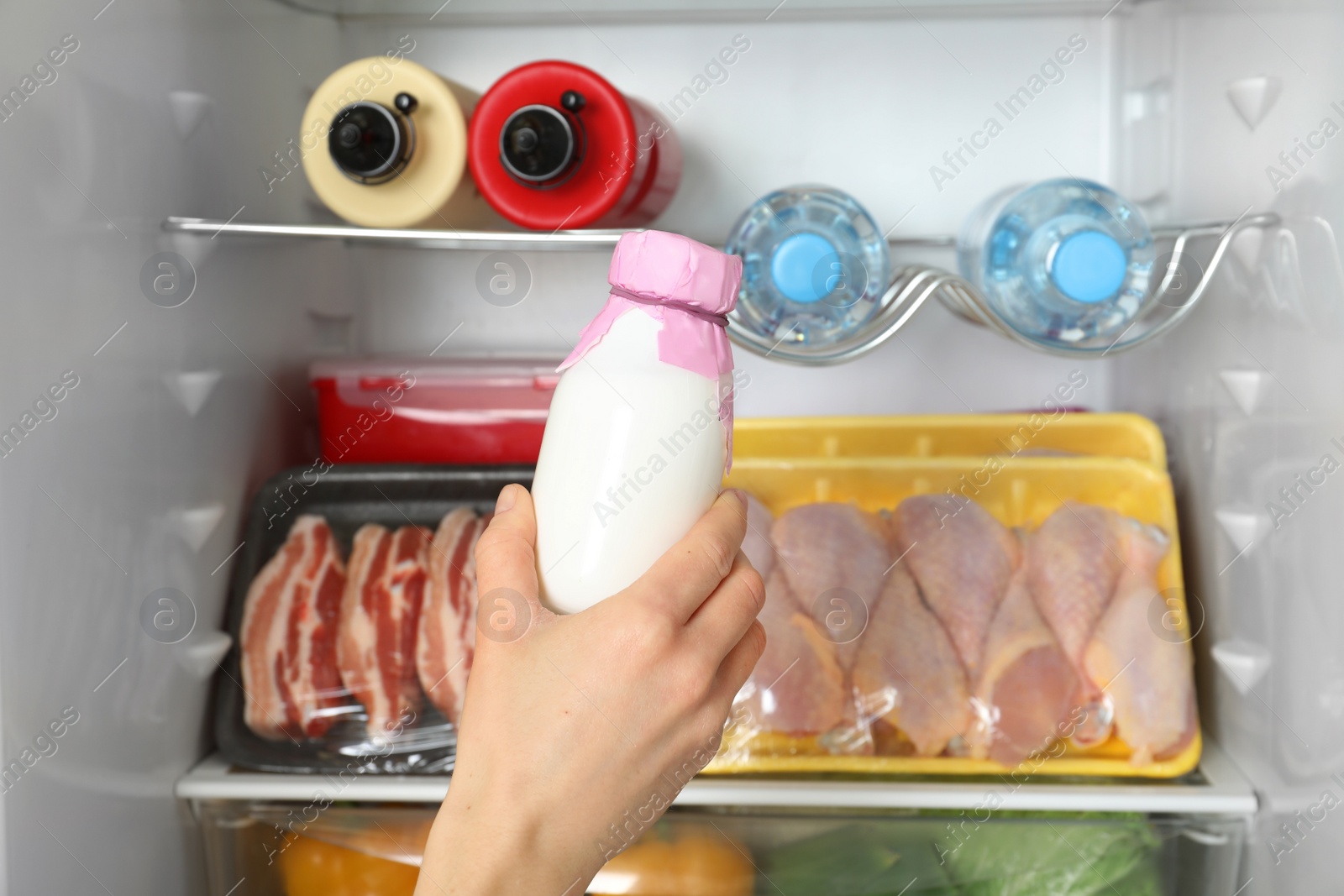 Photo of Woman taking bottle of yogurt from refrigerator, closeup