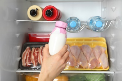 Woman taking bottle of yogurt from refrigerator, closeup