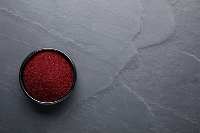 Photo of Bowl of dark red food coloring on grey table, top view. Space for text