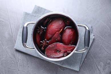 Tasty red wine poached pears and spices in pot on grey table, top view