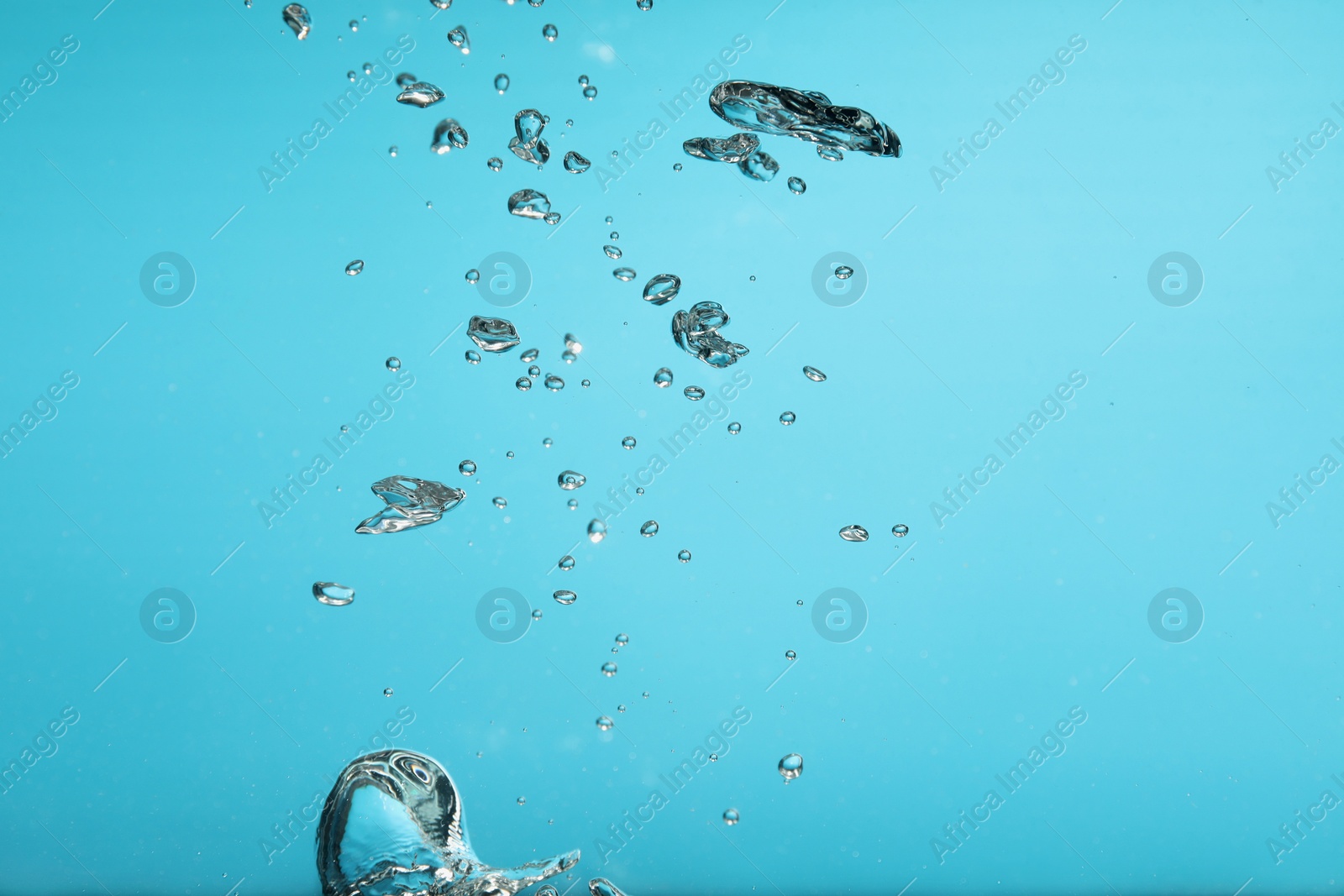 Photo of Air bubbles in water on light blue background