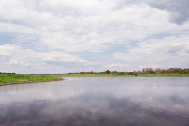 Photo of River near village under sky with clouds. Picturesque landscape