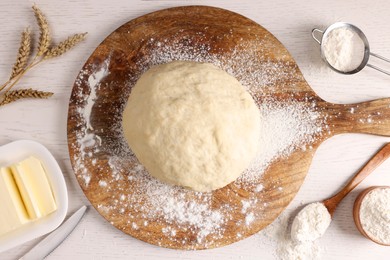 Fresh dough sprinkled with flour and other ingredients on white wooden table, flat lay