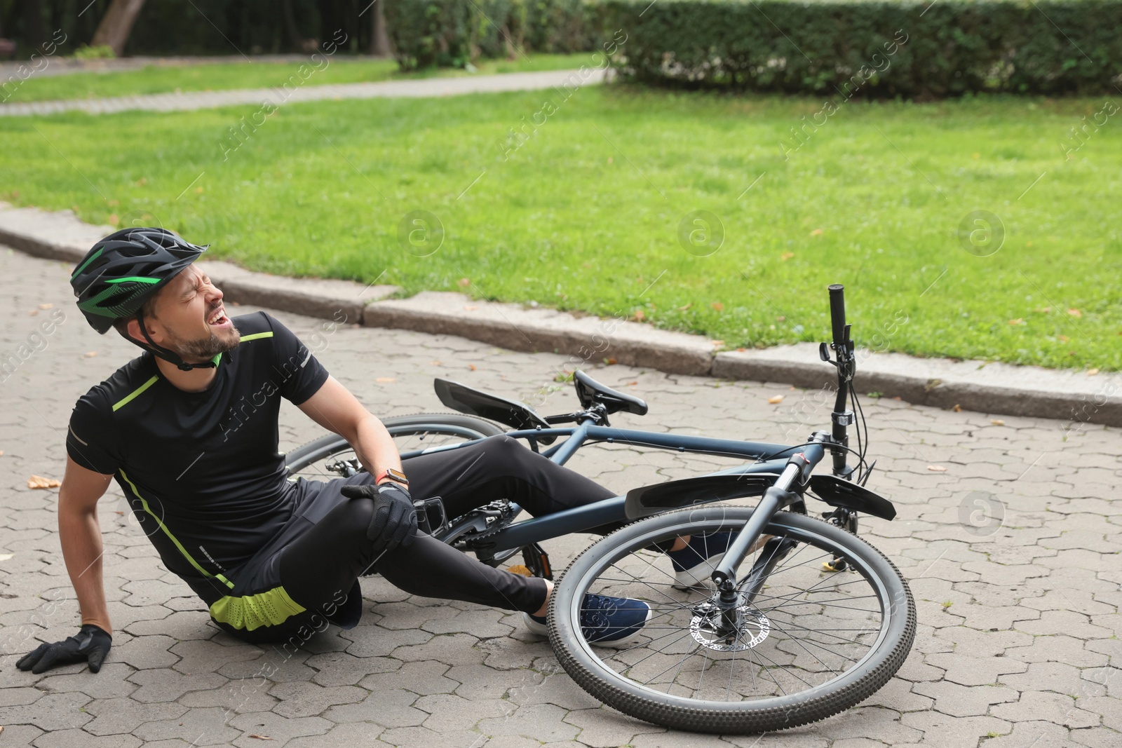 Photo of Man with injured knee near bicycle outdoors