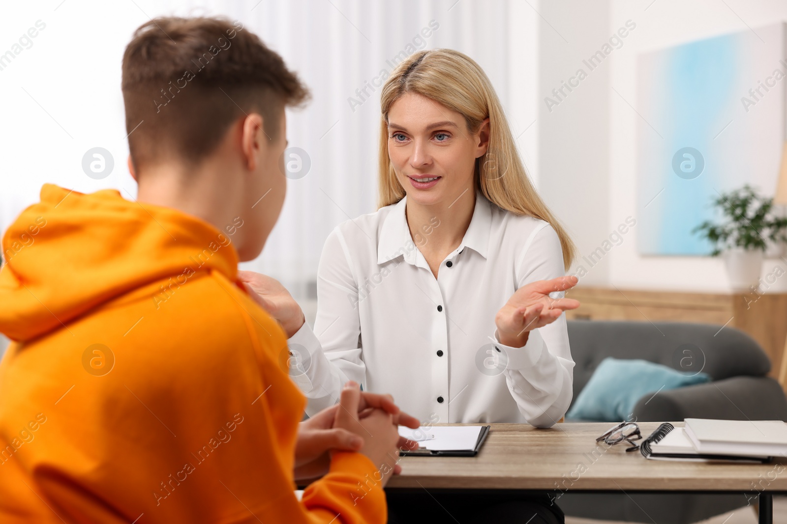 Photo of Psychologist working with teenage boy at table in office