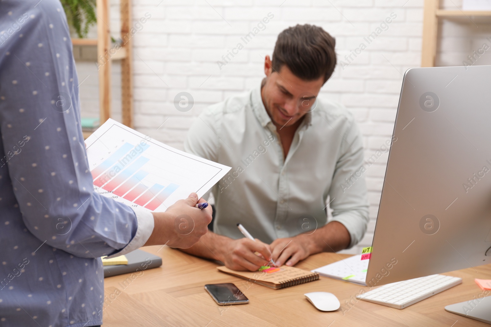 Photo of Colleagues making schedule using calendar in office