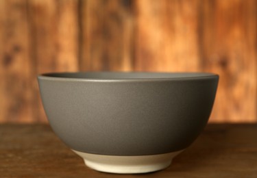 Photo of Stylish empty ceramic bowl on wooden table, closeup. Cooking utensil