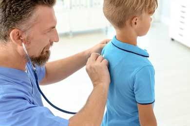 Photo of Male medical assistant examining child in clinic