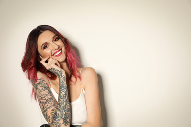 Photo of Beautiful woman with tattoos on arms against light background. Space for text
