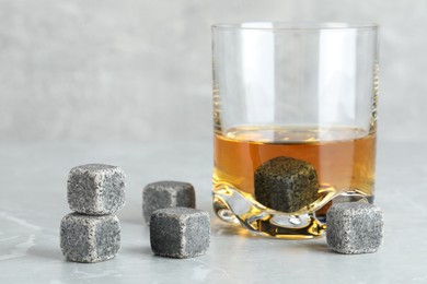 Whiskey stones and drink in glass on light marble table, closeup