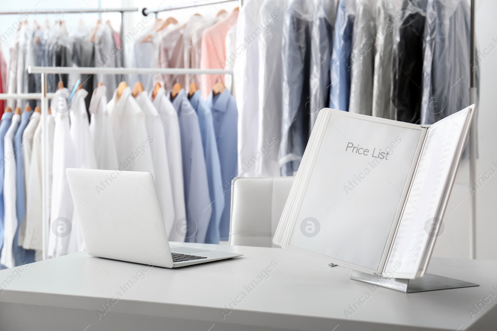 Photo of Workplace of receptionist with laptop and price list at dry-cleaner's