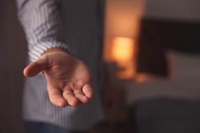 Man offering helping hand on blurred background, closeup. Space for text