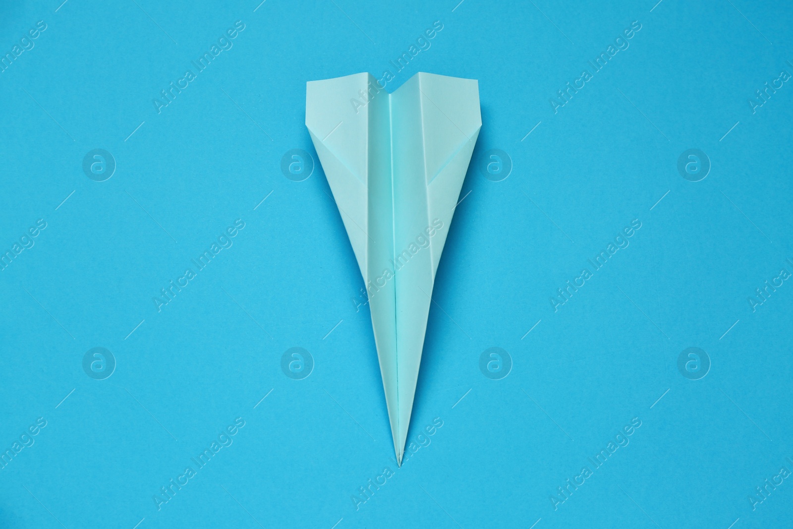 Photo of Paper plane on light blue background, top view