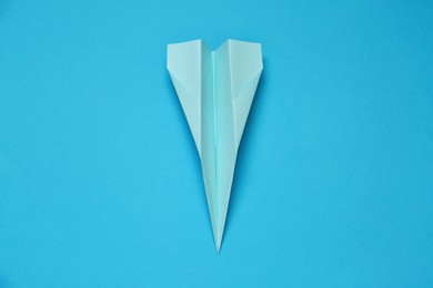 Paper plane on light blue background, top view