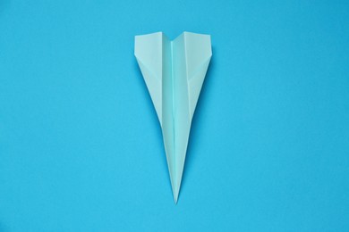 Photo of Paper plane on light blue background, top view